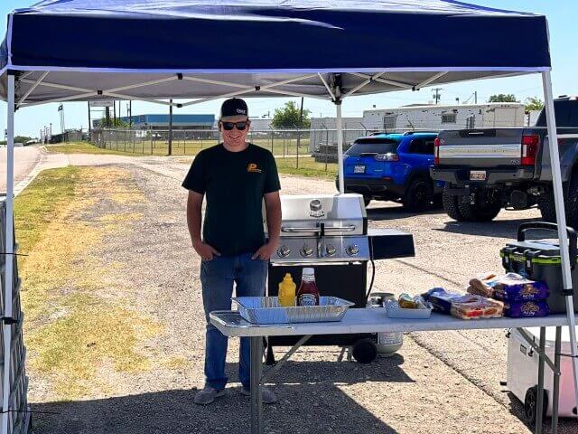 An employee stands ready to give out free hot dogs during a food drive in the HSC parking lot